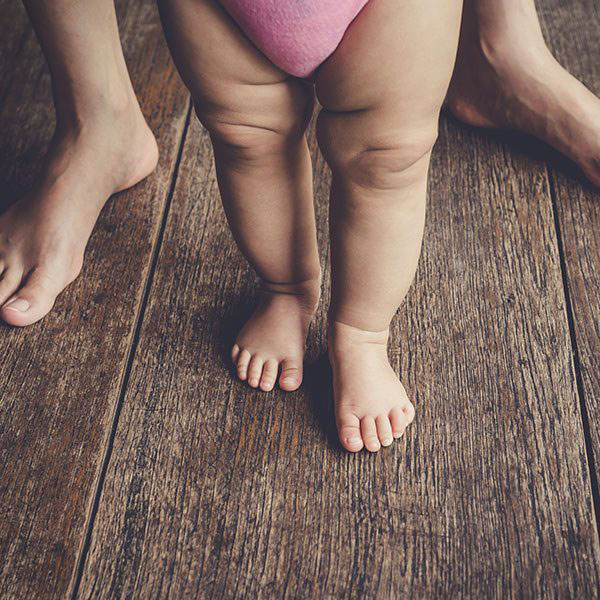 mom and infants feet on hardwood floor